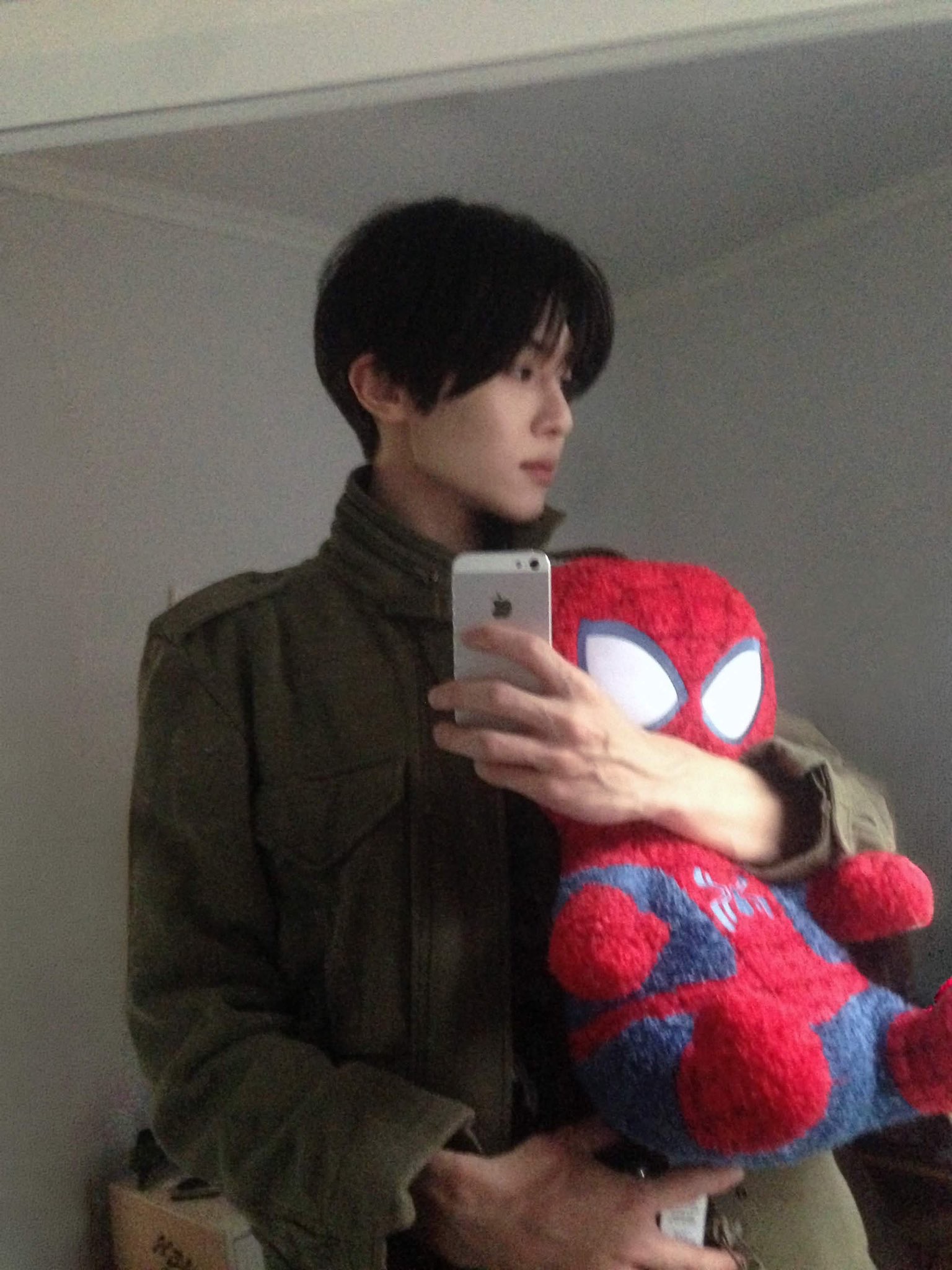 카키색 야상을 입고 스파이더맨 인형을 안은 채 옆을 보며 찍은 거울 셀카