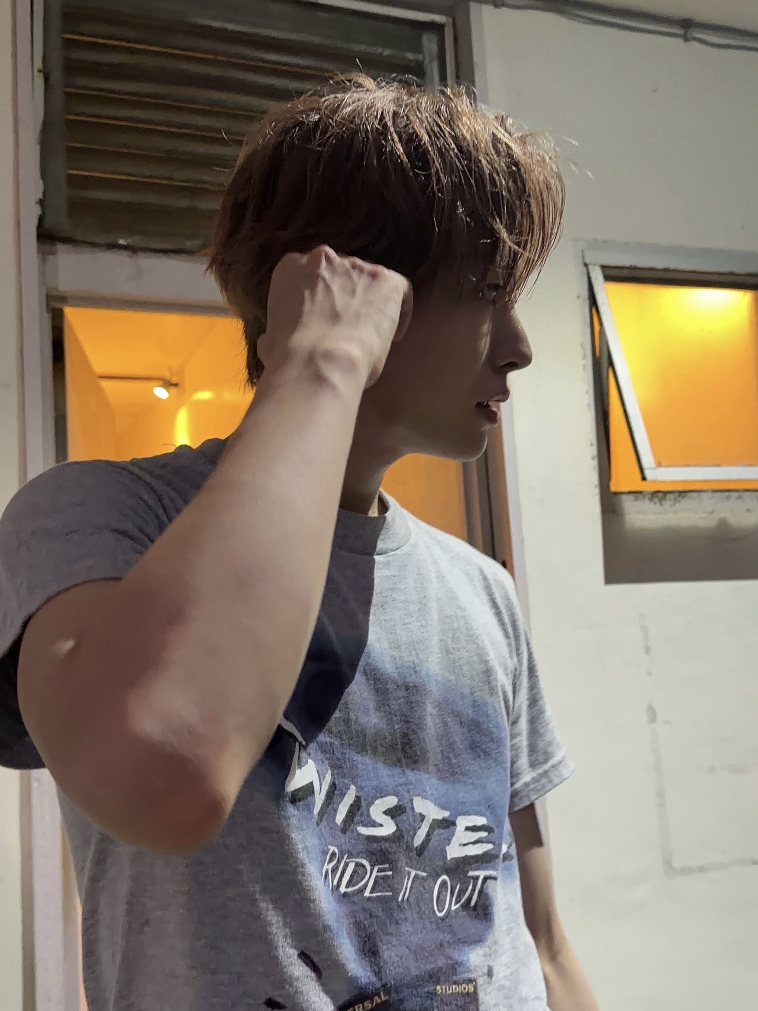 노란 불빛이 새어 나오는 창문 앞��서 머리를 넘기는 옆모습